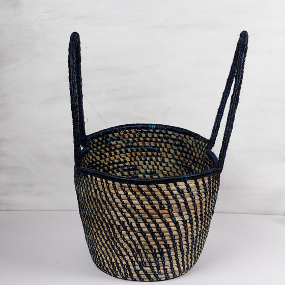 Traditional handwoven picnic basket made from sustainable materials. The basket has an intricate weaving pattern. The basket has sturdy handles for easy transport and is perfect for outdoor picnics, beach trips, or as a stylish storage solution at home.